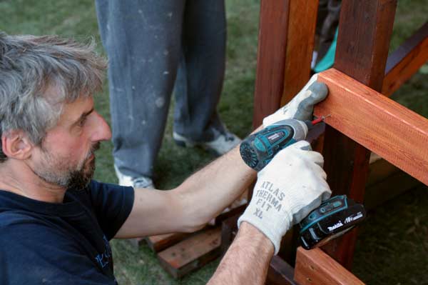 guydrill Keefer secures the ladder that will lead up to a new wooden playhouse for the children. The house was donated to the family by Home Depot. (Mitch Thompson photo)